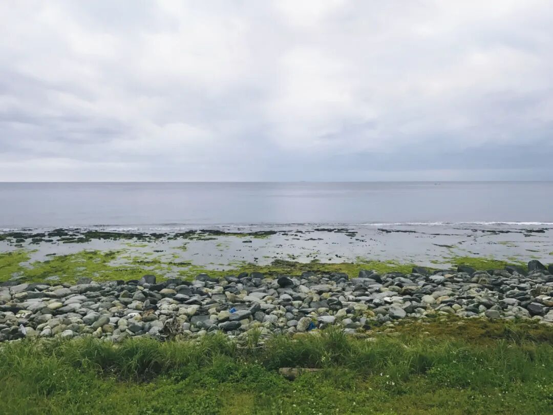 Sunrise over the Pacific Ocean from Green Island, with a cloudy sky.