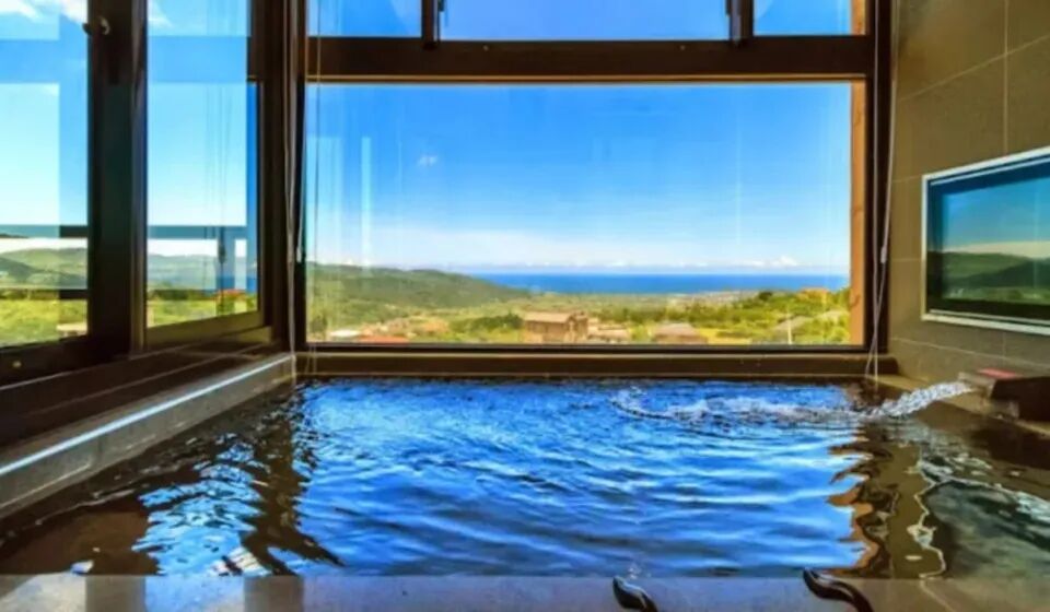 A luxurious hot spring pool with expansive views of the ocean from a private room.