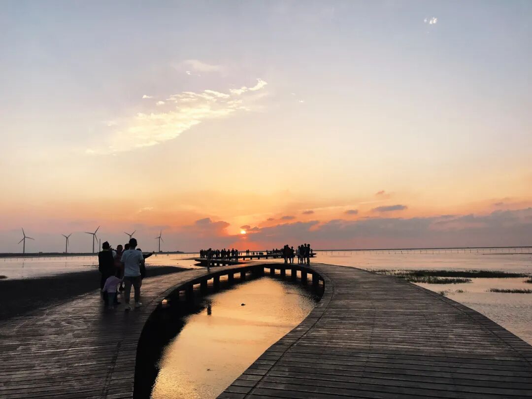 Close-up of the Gaomei Wetlands wooden boardwalk, gracefully leading to the horizon, reflecting fading light.