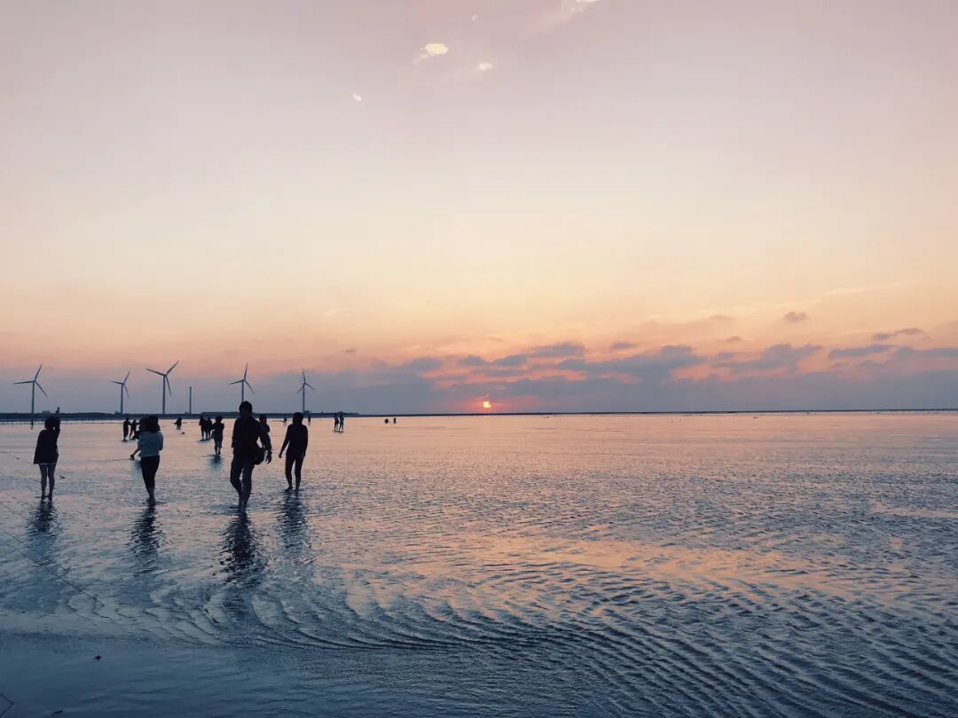 Gaomei Wetlands wooden boardwalk, bathed in soft, inviting sunset glow, beckoning visitors to explore.