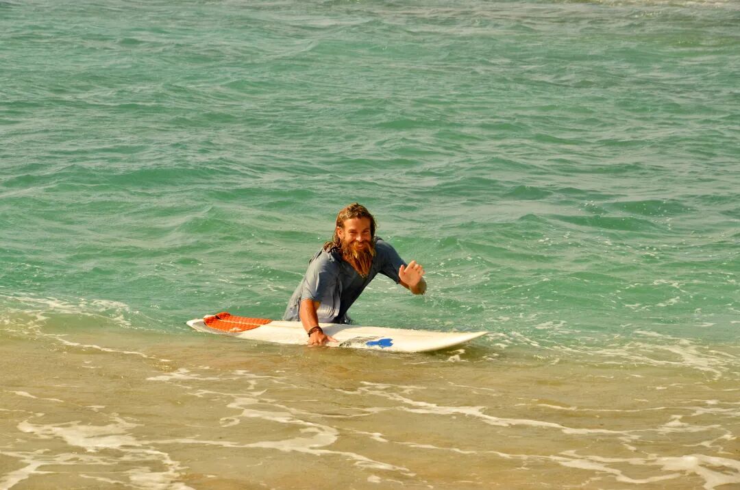 A lone surfer paddling out into the ocean from a small bay, seeking waves