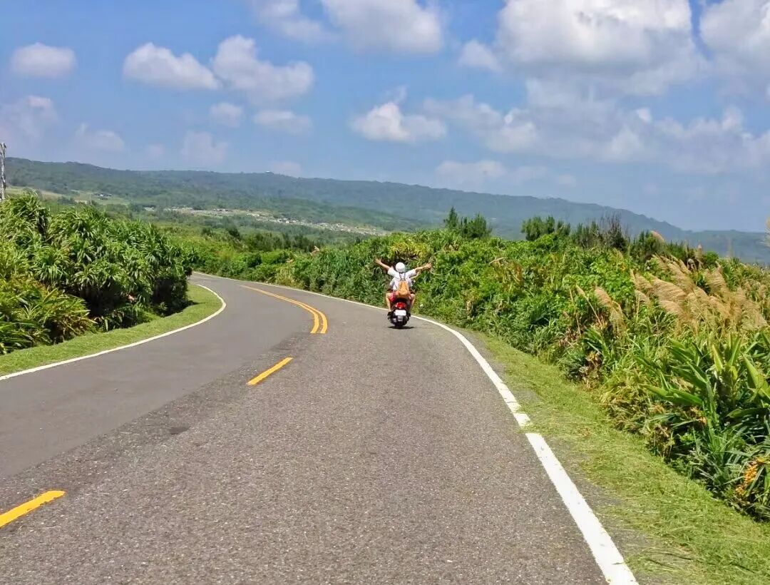 Scenic coastal road in Kenting, with the vast ocean on one side and green hills on the other