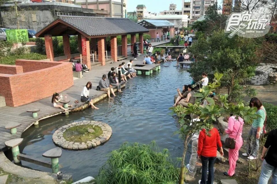 A luxurious outdoor hot spring pool at a resort, surrounded by mountains and lush trees.