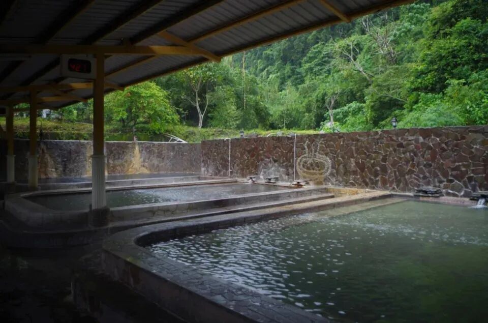 A woman's hand testing clear, mineral-rich hot spring water, known for skin benefits.