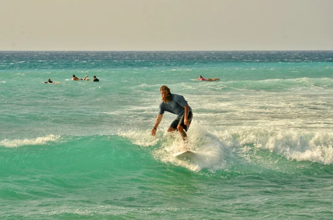 A surfer waiting for a wave on their board in a small bay, calm before the action