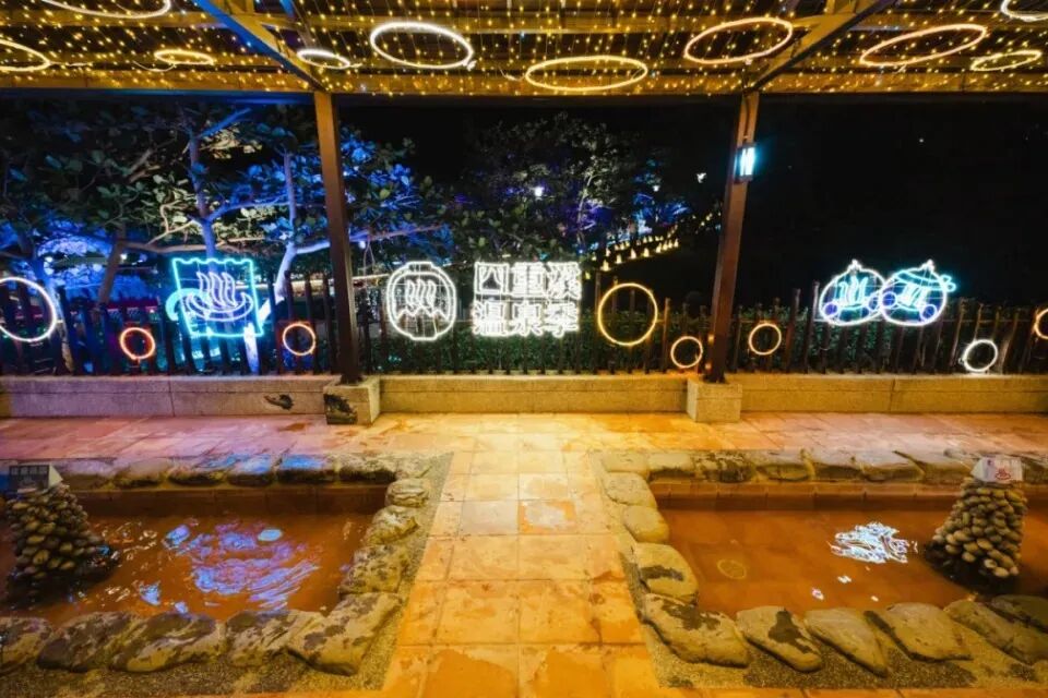 Colorful light installations illuminate a beautiful hot spring park during a festival.