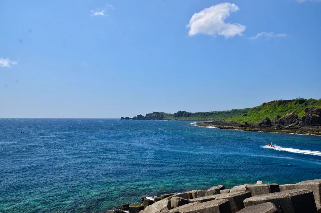 Small boats and vibrant clear waters at Houbihu Fishing Harbor, a popular spot