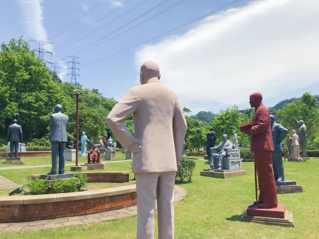 A bronze statue of Chiang Kai-shek seated thoughtfully, nestled among the verdant greenery of Cihu Statue Park.